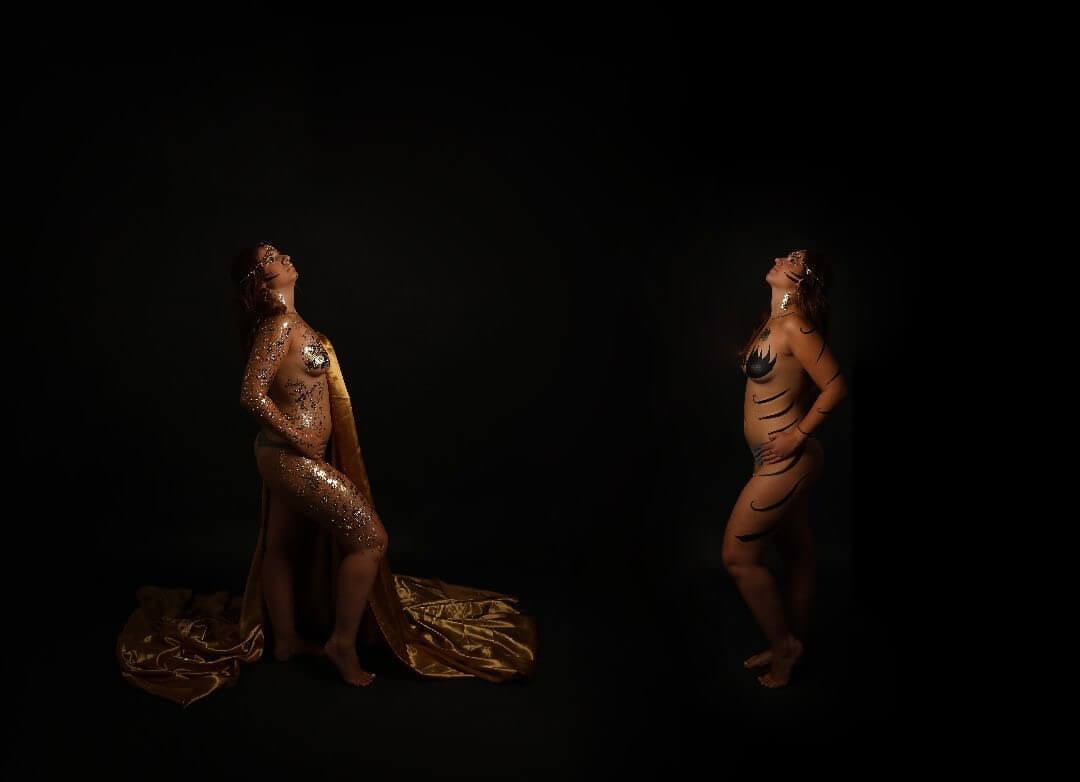 Deux femmes majestueuses posent contre un fond sombre, l'une ornée de peinture dorée étincelante et l'autre peinte en tigre, dégageant puissance et grâce.
