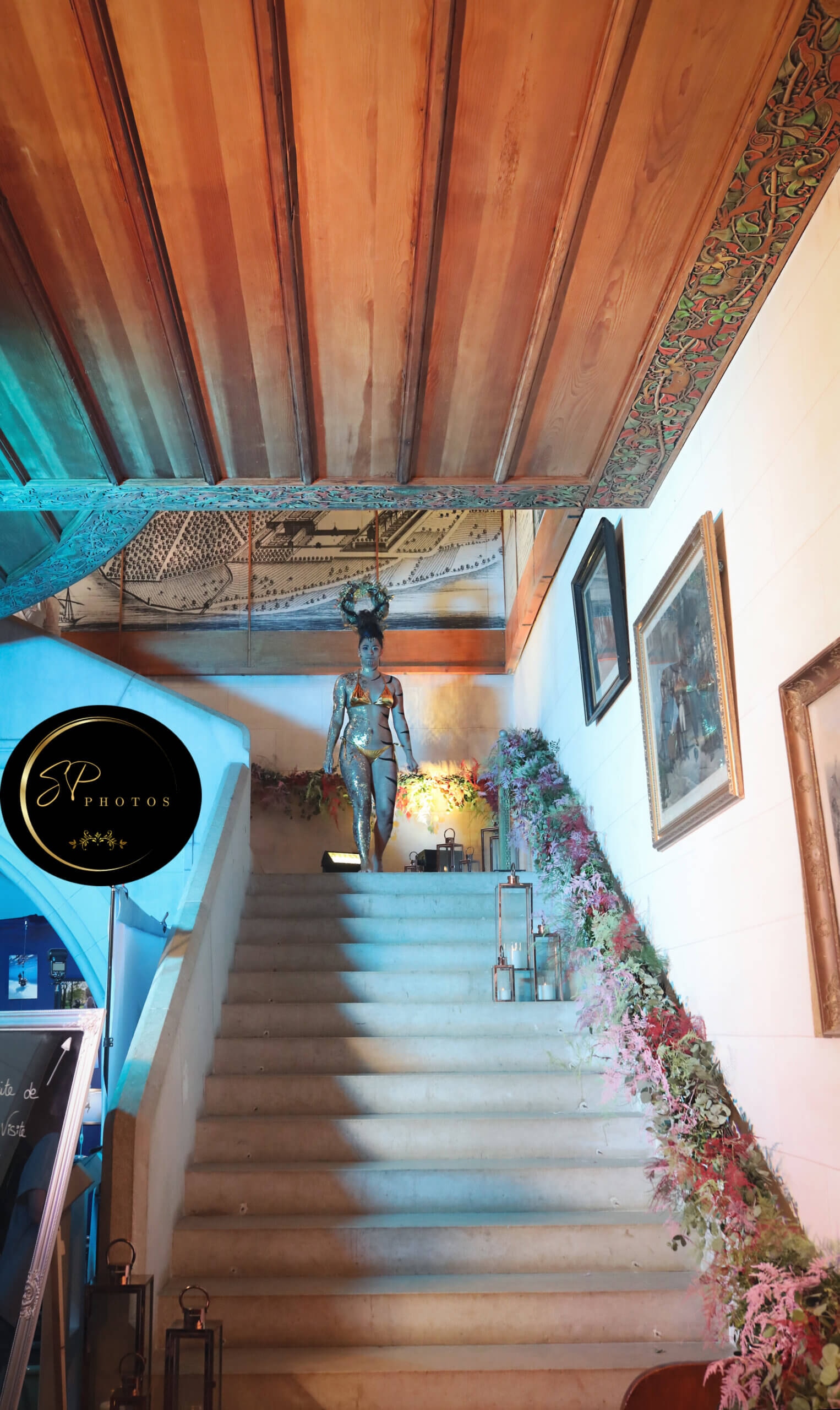 Un escalier magnifiquement conçu, orné d'éléments décoratifs et illuminé par une lumière douce, menant à une zone bien décorée, avec des lanternes stylées à gauche et une sculpture frappante au sommet.